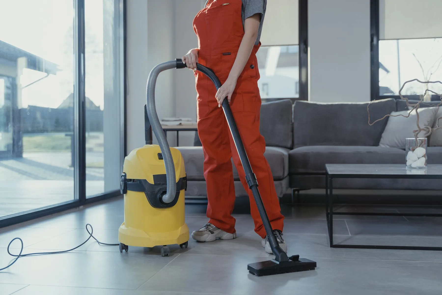Schoonmaker stofzuigt de vloer van een ruimte met grote ramen